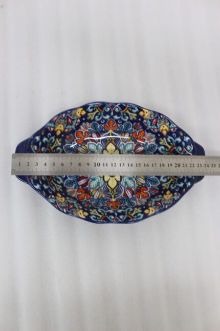 9.5-inch decorative Marrakech oval ceramic serving bowl with intricate blue, orange, and yellow hand-painted floral patterns resting on a marble countertop