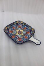 Square 6.5-inch Marrakech ceramic serving dish with colorful mosaic mandala patterns and an integrated handle on a wooden table.