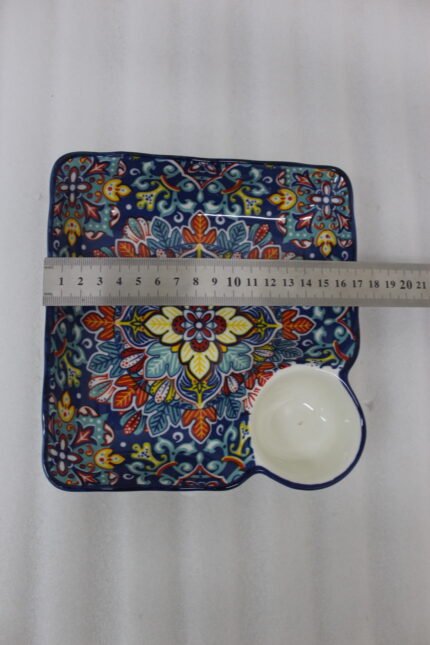 Square hand-painted Moroccan ceramic serving dish with colorful Marrakech floral pattern and built-in dip bowl on a wooden table.