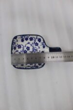 Square ceramic Moroccan dip bowl with blue floral patterns and integrated handle resting on a light marble kitchen countertop.