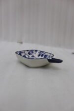 Square ceramic Moroccan dip bowl with blue floral patterns and integrated handle resting on a light marble kitchen countertop.