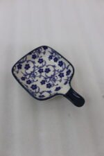 Square ceramic Moroccan dip bowl with blue floral patterns and integrated handle resting on a light marble kitchen countertop.