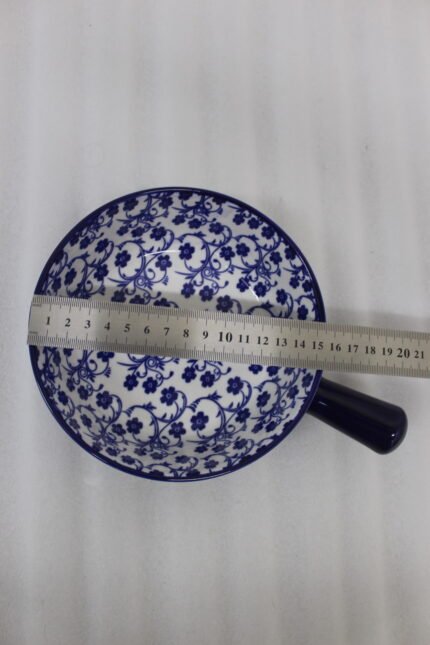 Decorative 6-inch blue and white floral ceramic Marakesh serving dish with single side handle on a wooden kitchen countertop.