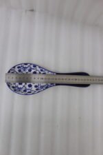 Blue and white ceramic spoon rest with Moroccan floral pattern resting on a marble countertop.