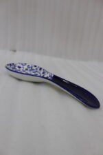 Blue and white ceramic spoon rest with Moroccan floral pattern resting on a marble countertop.