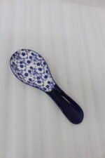 Blue and white ceramic spoon rest with Moroccan floral pattern resting on a marble countertop.