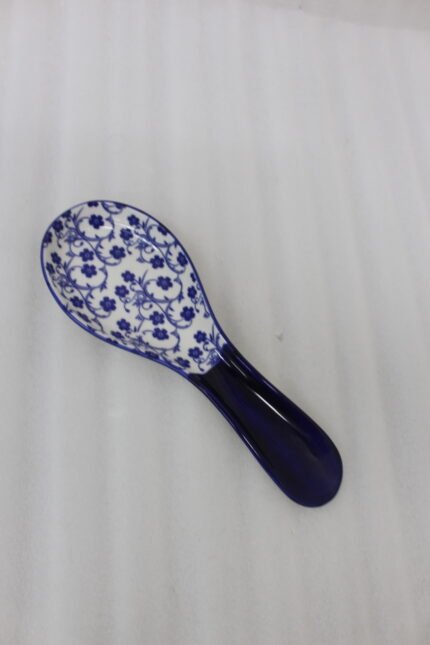 Blue and white ceramic spoon rest with Moroccan floral pattern resting on a marble countertop.