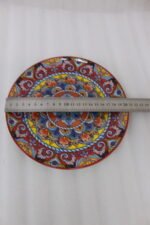Two decorative Marrakech ceramic plates with vibrant colorful mosaic mandala patterns resting on a rustic wooden table.