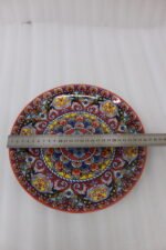Two decorative Marrakech ceramic plates with vibrant colorful mosaic mandala patterns resting on a rustic wooden table.