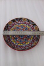 Three vibrant ceramic decorative Moroccan plates featuring intricate mandala patterns in red, blue, and yellow arranged on a wooden countertop.