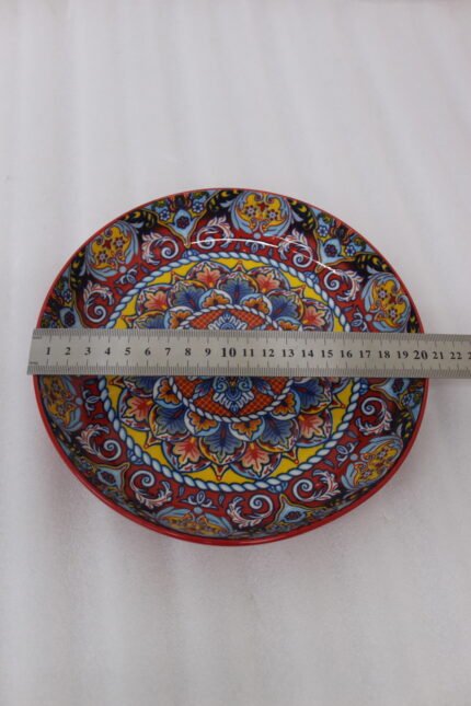 Three vibrant ceramic decorative Moroccan plates featuring intricate mandala patterns in red, blue, and yellow arranged on a wooden countertop.