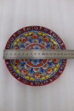 Three vibrant ceramic decorative Moroccan plates featuring intricate mandala patterns in red, blue, and yellow arranged on a wooden countertop.