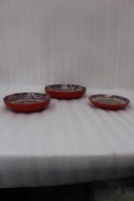 Three vibrant ceramic decorative Moroccan plates featuring intricate mandala patterns in red, blue, and yellow arranged on a wooden countertop.