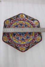 Hexagonal decorative Marakesh plate with vibrant hand-painted Moroccan tile mosaic pattern on a wooden kitchen table.