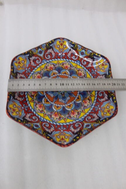 Hexagonal decorative Marakesh plate with vibrant hand-painted Moroccan tile mosaic pattern on a wooden kitchen table.