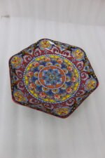 Hexagonal decorative Marakesh plate with vibrant hand-painted Moroccan tile mosaic pattern on a wooden kitchen table.