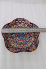 Colorful star-shaped ceramic Marrakesh decorative plate with intricate Moroccan mosaic pattern on a wooden table.