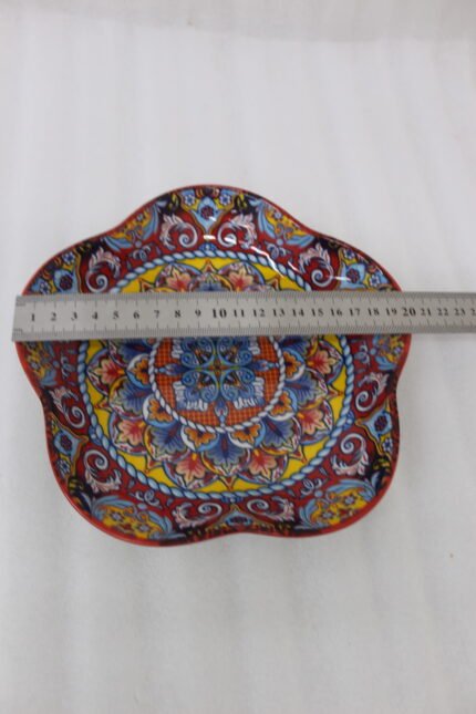 Colorful star-shaped ceramic Marrakesh decorative plate with intricate Moroccan mosaic pattern on a wooden table.