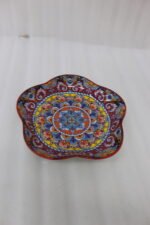 Colorful star-shaped ceramic Marrakesh decorative plate with intricate Moroccan mosaic pattern on a wooden table.