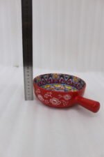 6-inch red ceramic Marrakech serving bowl with vibrant hand-painted geometric interior patterns and a single side handle sitting on a wooden kitchen island