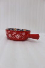 6-inch red ceramic Marrakech serving bowl with vibrant hand-painted geometric interior patterns and a single side handle sitting on a wooden kitchen island