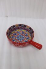 6-inch red ceramic Marrakech serving bowl with vibrant hand-painted geometric interior patterns and a single side handle sitting on a wooden kitchen island