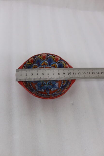 4-inch hand-painted decorative Marrakech ceramic piyali bowl with vibrant blue, yellow, and red pattern resting on a wooden table.
