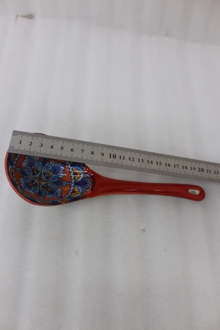 Hand-painted ceramic spoon rest with colorful Moroccan pattern resting on a wooden countertop.