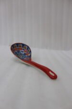 Hand-painted ceramic spoon rest with colorful Moroccan pattern resting on a wooden countertop.