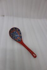 Hand-painted ceramic spoon rest with colorful Moroccan pattern resting on a wooden countertop.