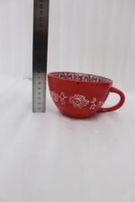Large red ceramic Marrakech mug with vibrant bohemian interior patterns resting on a round wood slice coaster.