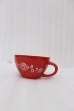 Large red ceramic Marrakech mug with vibrant bohemian interior patterns resting on a round wood slice coaster.