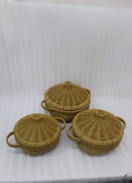 3-piece handwoven natural rattan basket set with fitted lids and side handles sitting on a light wooden table