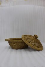3-piece handwoven natural rattan basket set with fitted lids and side handles sitting on a light wooden table