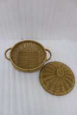 3-piece handwoven natural rattan basket set with fitted lids and side handles sitting on a light wooden table