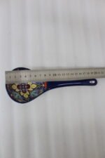 Handcrafted decorative Marrakech ceramic spoon with vibrant blue, yellow, and red bohemian floral patterns resting on a marble countertop