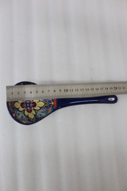 Handcrafted decorative Marrakech ceramic spoon with vibrant blue, yellow, and red bohemian floral patterns resting on a marble countertop