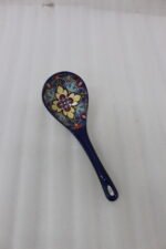 Handcrafted decorative Marrakech ceramic spoon with vibrant blue, yellow, and red bohemian floral patterns resting on a marble countertop