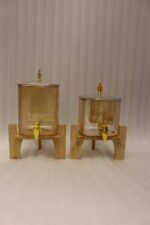 Ribbed amber glass beverage dispenser with gold tap and pineapple lid finial on a wooden stand