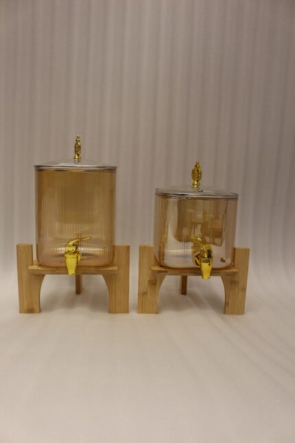 Ribbed amber glass beverage dispenser with gold tap and pineapple lid finial on a wooden stand
