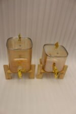Ribbed amber glass beverage dispenser with gold tap and pineapple lid finial on a wooden stand