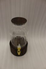 Elegant 3L ribbed glass drink dispenser sitting on a dark wooden base with a gold spigot on a kitchen counter