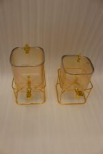 Two amber fluted glass beverage dispensers on gold metal stands resting on a modern kitchen counter