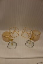 Two amber fluted glass beverage dispensers on gold metal stands resting on a modern kitchen counter