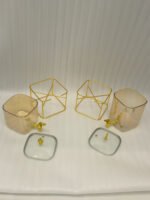 Two amber fluted glass beverage dispensers on gold metal stands resting on a modern kitchen counter