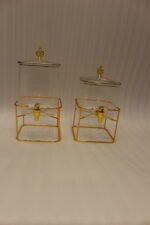Two ribbed glass beverage dispensers with gold spigots and metal stands on a kitchen counter