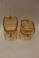 Amber shaded ribbed glass beverage dispenser with gold spigot, leather handle, and gold metal stand on a marble countertop