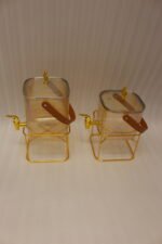 Amber shaded ribbed glass beverage dispenser with gold spigot, leather handle, and gold metal stand on a marble countertop