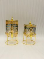 Luxury amber glass beverage dispenser with intricate blue pattern on a decorative gold metal stand