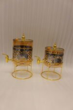 Luxury amber glass beverage dispenser with intricate blue pattern on a decorative gold metal stand